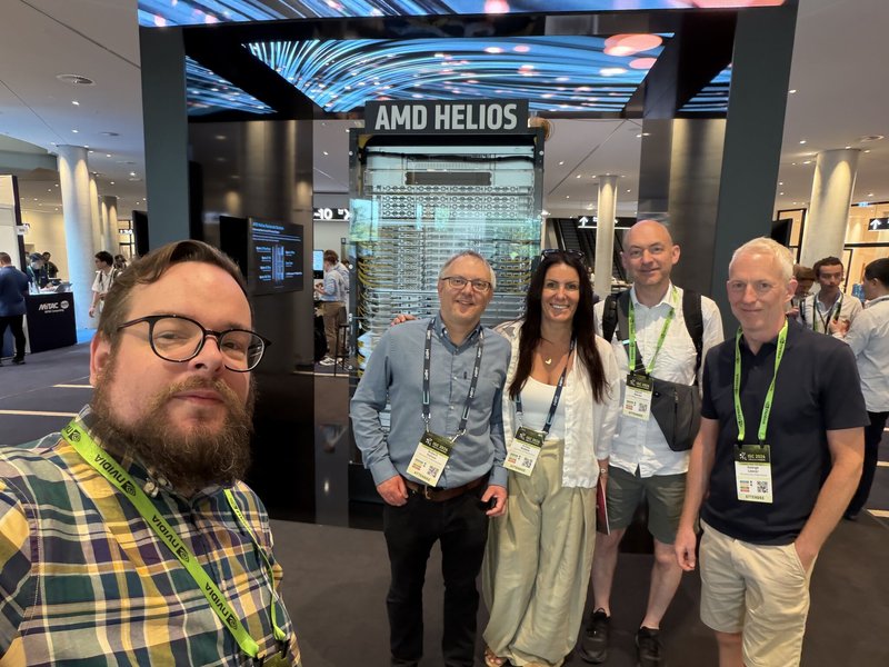 A photo of the 5 attendees from IT Services. A man with glasses, a beard and yellow shirt is taking a selfie of everyone, There are 3 men and 1 woman in the group. One man has dark hair and glasses, another is tall and bald wearing a white shirt. The other is blonde and is wearing a dark shirt and tailored shorts. The woman has long dark brown hair and is wearing long beige trousers and a white top.