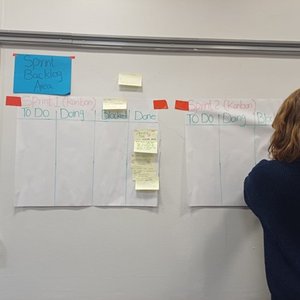 Someone with their back to the camera sorting out post it notes on a white wall