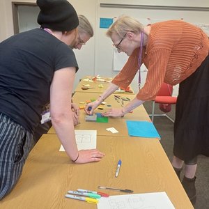 Three people standing at a desk playing with lego