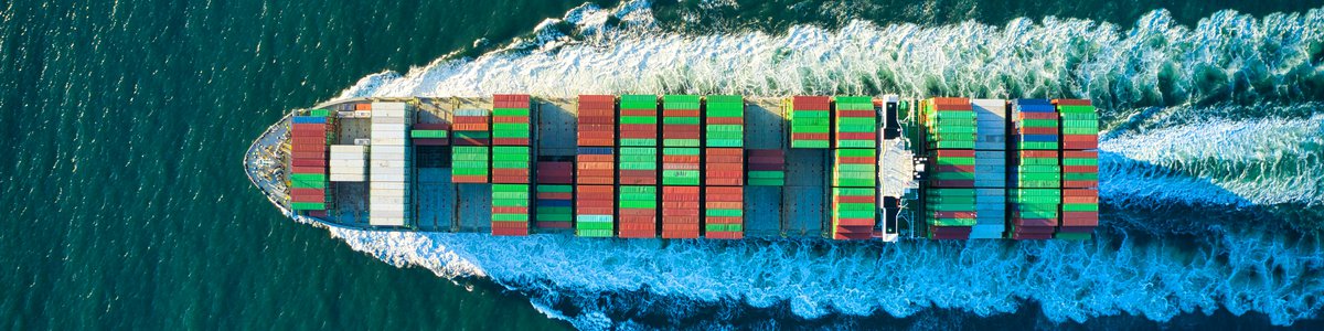 Photo of a container ship taken from above ploughing through the blue sea