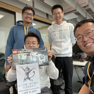 Four Year in Industry students smiling at the camera. One of them is holding a box of lego